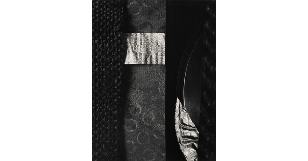 A black-and-white abstract photograph of materials of contrasting textures laid flat to form shapes.