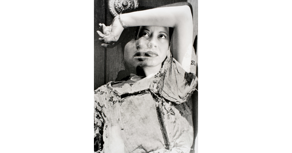 A black-and-white, double-exposure photograph of two portraits of women posed with their arm over their heads and gazing upward.