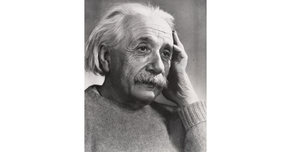 A black-and-white photograph of an older White man with white hair and mustache holding one hand up to the side of his face.